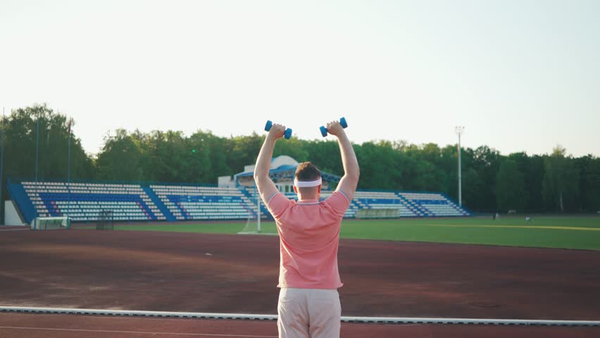 Focused funny motivated overweight man in sportswear during morning workout. Exercises for muscle development.