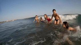 Cheerful children funny jumping in the sea waves. High quality FullHD footage