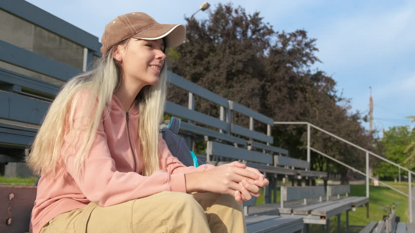 Teen cheer for favorite team on stadium. A happy smiling teen girl enjoy the favorite team game on tribunes during day time.