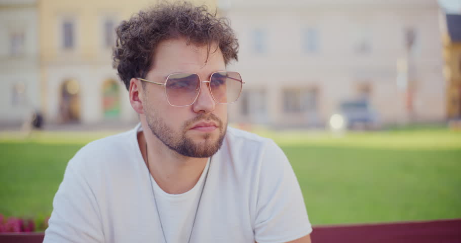 Contemplative young man with hand on chin looking around in garden
