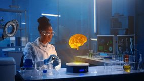 Medium-sized video capturing a dark-skinned female scientist wearing glasses and a lab coat sitting in a laboratory, researching brain hologram displayed in front of her. - Powered by Shutterstock - Get 15% off with code: PIKWIZARD15