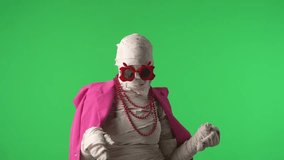 Green screen isolated chroma key video capturing a mummy wearing pink jacket, necklace and glasses acting fancy and elegantly.