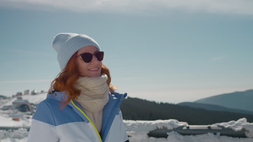 Happy female enjoy winter vacation raising hands high in the air. Tourist walking through snow in the mountains.