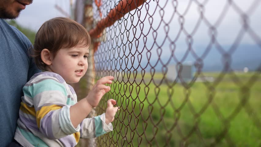 a small child in the arms of his mother at the fence grating Royalty-Free Stock Footage #1109689425