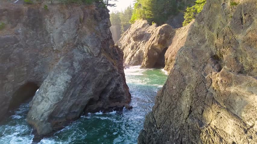 Oregon Coast Highway 101 Viewpoint of "Natural Bridge" rock formations. 4K Aerial drone flying through canyon, waves crashing, forming natural arches in the rocky cliffs.