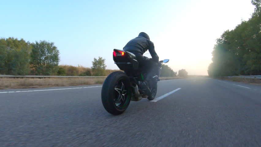 Aerial shot of motorcyclist riding on modern sport motorbike at autumn highway. Biker racing his motorcycle on country road. Guy driving bike during trip. Concept of freedom and adventure at journey