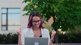 Happy surprised young woman sitting with a laptop outdoor receiving good news. Beautiful female student celebrating great results of exams. Back to school, knowledge day. - Powered by Shutterstock - Get 15% off with code: PIKWIZARD15