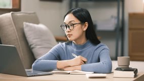 Young adult asian student woman taking notes while using laptop computer at home. Asian female learning online listening virtual video call. Business and education concept. - Powered by Shutterstock - Get 15% off with code: PIKWIZARD15