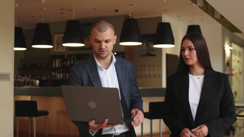 Confident male leader negotiating with business woman, explaining the benefits of a contract in the lobby, advising a corporate client presenting a business proposal. Royalty-Free Stock Footage #1109711517
