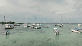 Drone flying over boats and catamarans moored in Bayahibe Bay, La Romana in Dominican Republic. Aerial forward ascending and sky for copy space
