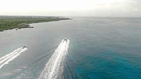 Speedboats navigating together in the same direction along Bayahibe coast leaving white wakes, Dominican Republic. Aerial drone view