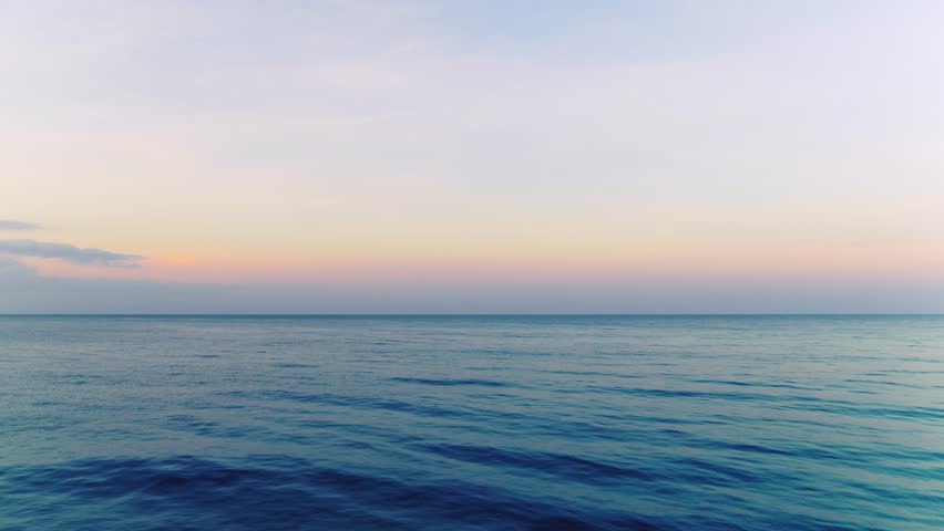 Aerial pink dawn in the morning sky over the ocean. Morning dawn on the sea horizon. Calm seascape. Summer ideal natural landscape. Blue ocean waves.