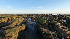 Moving between the rocks of a sea beach on a sunny day. Video in 4K.