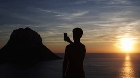 Man recording a video of the sunset with his mobile phone