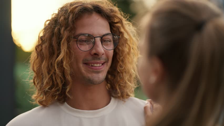 POV: A happy curly-haired guy in a white t-shirt and glasses is talking to his girlfriend Royalty-Free Stock Footage #1109729287