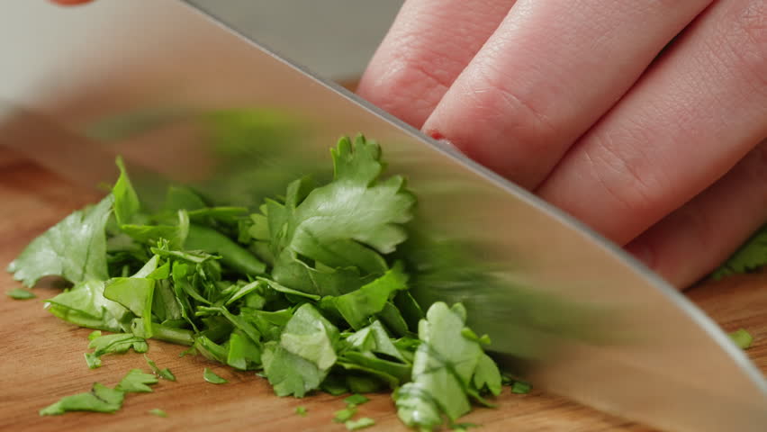 Cilantro parsley cutting by knife close up, chef chop cut coriander aromatic, traditional asian and Mexican cuisine herb studio shot.