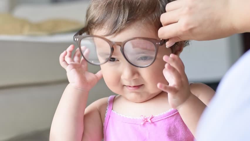 close-up of a little latina baby playing with glasses, trying to put on big glasses Royalty-Free Stock Footage #1109732645