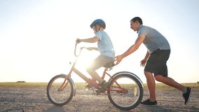 family play in the park. father teaching son to ride a bike. happy family kid dream concept. son learn to ride bike silhouette. father supporting child son riding bike summer in the sunset park - Powered by Shutterstock - Get 15% off with code: PIKWIZARD15