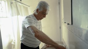 Elderly man brushes teeth in front of bathroom mirror reflection, morning daily ritual, depicting domestic lifestyle in old age routine - Powered by Shutterstock - Get 15% off with code: PIKWIZARD15