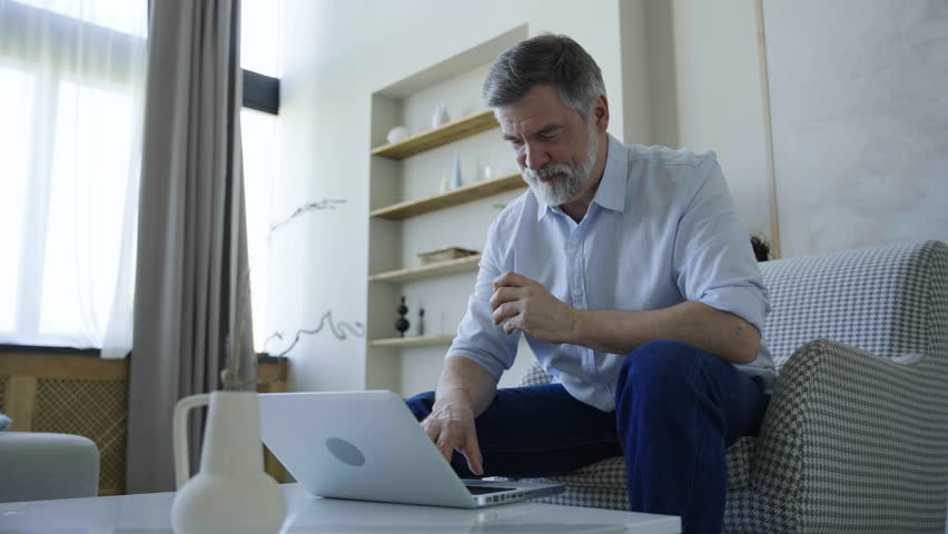 Mature man using laptop and working in house. Freelancer office concept | Shutterstock HD Video #1109744743