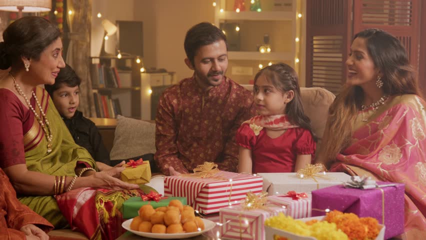 Ethnic Hindu Indian happy family members in traditional wear sitting indoors together and exchanging or giving gifts Boxes to each other on the religious occasion of Diwali festival in decorated House Royalty-Free Stock Footage #1109746437