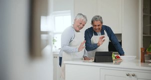 Kitchen, greeting and senior couple with a tablet, video call and communication with connection, apron and cooking. Home, happy elderly man and old woman with technology, online instructions and wave