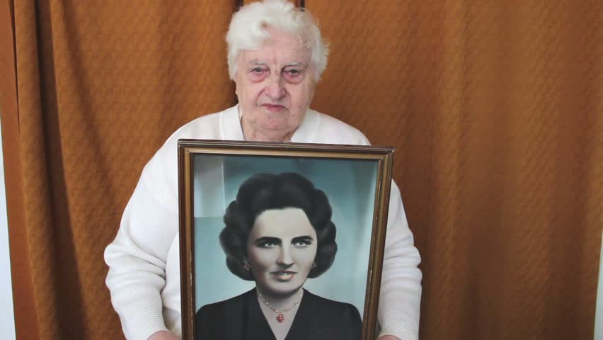 85 years old woman is showing her portrait when she was young.