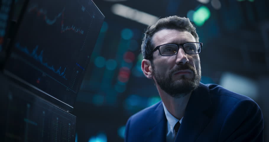Close Up Portrait of a Smart and Thoughtful Stock Exchange Broker. Adult Man in Glasses Looking at Computer Screens, Analyzing Stock Exchange Market Data, Brainstorming a Successful Buying Strategy Royalty-Free Stock Footage #1109752725
