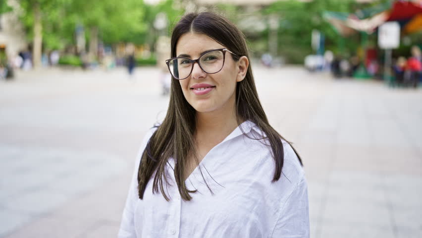 Young beautiful hispanic woman wearing glasses smiling happy in the streets of Madrid