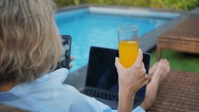 Female freelancer working outdoors at the poolside at sunny day