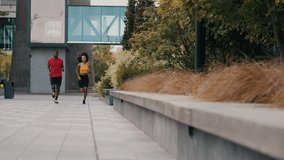 Lovely african american couple dressed in sports uniform jogging together near residential buildings. Energetic man and woman actively engaging in sports during romantic date. - Powered by Shutterstock - Get 15% off with code: PIKWIZARD15