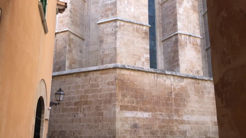 Tilt up and pan shot revealing Mallorca Cathedral shot from sunlit alley in Palma. Royalty-Free Stock Footage #1109761077