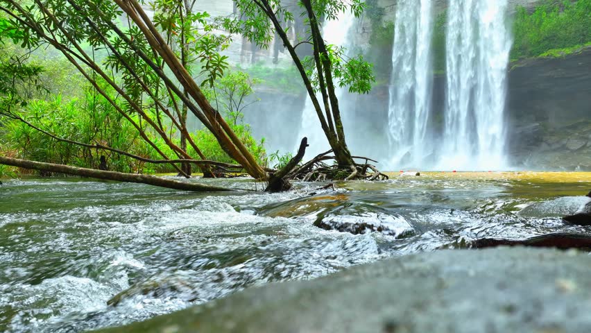Spectacular waterfall cascading from towering cliff, enveloped by vibrant tropical greenery, a mesmerizing natural wonder. Huai Luang Waterfall, Thailand. Explore world's wonders concept.

