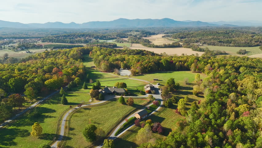 Aerial view of North Carolina countryside. Large expensive farmhouse surrounded with farm fields and dense woods close to Appalachian mountains