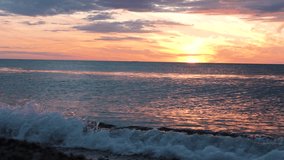 Red sunsets over sea video 4K. The sun touches horizon. Red sky, yellow sun and amazing sea. Summer sunset seascape. Atlantic Ocean beach sunsets. The sun in spindrift clouds Fantastic natural sunsets