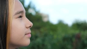 Portrait of a young beautiful preschool girl enjoying a warm summer day outdoors. Cute girl relaxing outdoors on the street, breathing fresh air. Profile of a child's face against the backdrop of a - Powered by Shutterstock - Get 15% off with code: PIKWIZARD15