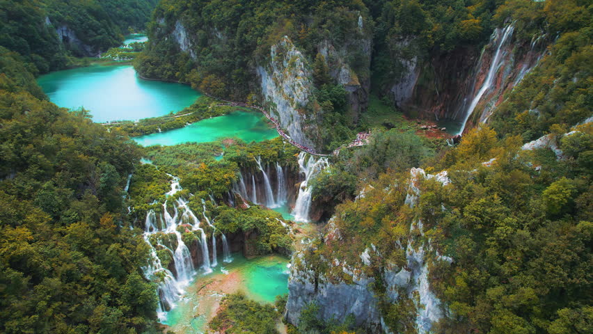 Waterfalls in the autumn forest flowing into lakes. Tourists visit famous Plitvice park in Croatia. Mountain streams with clear water.