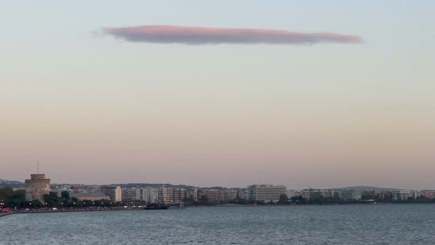 a sunset cloud in the shape o a ufo over a town in the sea thessaloniki in greece