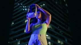 Young creative multi racial female putting on virtual reality headset in neon blue light night city. Girl enters digital internet 3D universe. Future generation immersive Social Media online metaverse - Powered by Shutterstock - Get 15% off with code: PIKWIZARD15