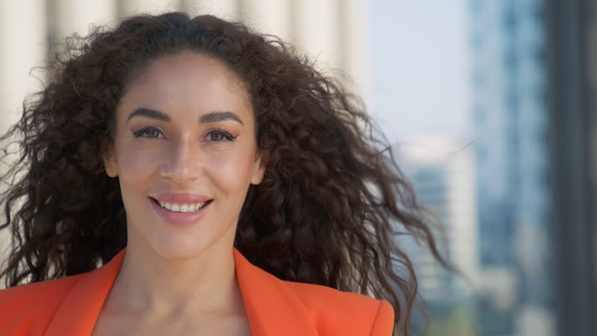 Beautiful smiling confident young latino ethnic woman. Close up of pretty face looking at camera posing alone with urban offices on background. Happy millennial ethnicity girl professional portrait 4K Royalty-Free Stock Footage #1109774123