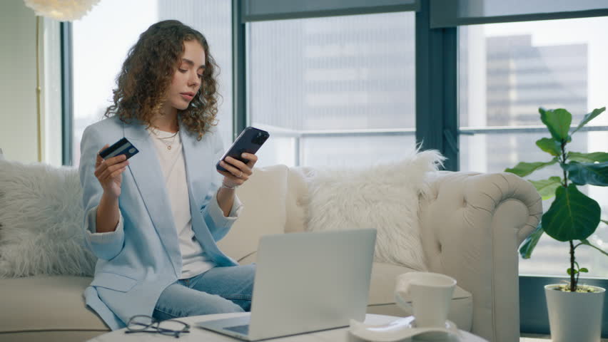 Happy elegant young woman holding credit card using instant mobile payments in modern apartment. Smiling beautiful girl making purchase on smartphone receiving cashback. E-banking app service concept Royalty-Free Stock Footage #1109774175