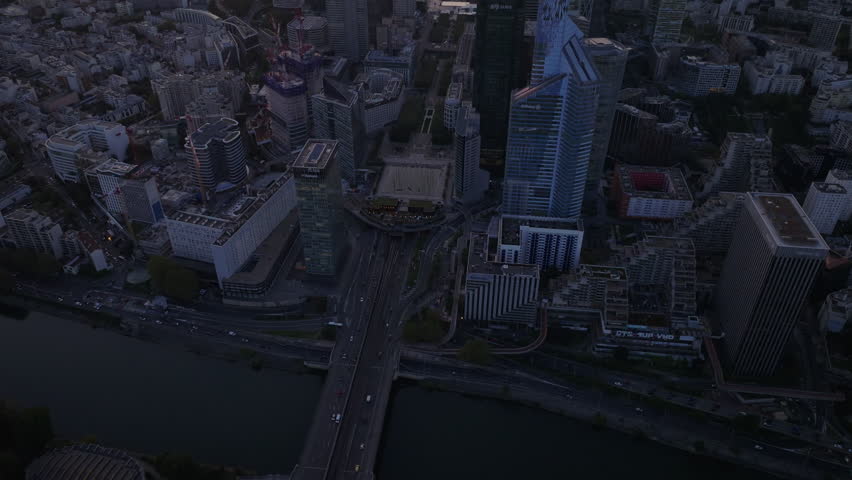 High angle view of busy trunk road and bridge over Seine River. Tilt up reveal of skyscrapers in modern La Defense district at dusk. Paris, France Royalty-Free Stock Footage #1109775653