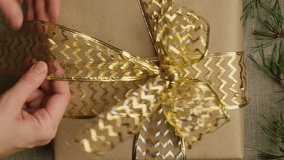 Vertical video. Hands tie ribbon bow on Christmas present. Boxing day, Christmas gift wrapping. 