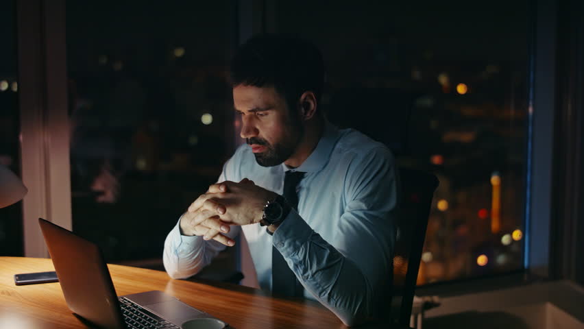 Worried manager sitting at night workplace looking laptop monitor close up. Overwhelmed businessman busy of corporate issues having overtime. Bearded office worker tired of computer work late evening. Royalty-Free Stock Footage #1109780463