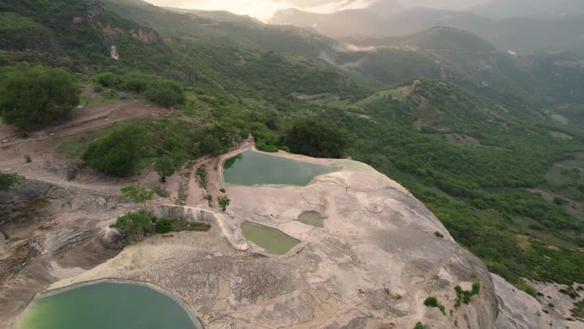 Rotating aerial of Hierve el Agua, which translates to "the water boils" - series of stunning mineral-laden rock formations that resemble cascading waterfalls, Mexico. Enchanting destination concept.