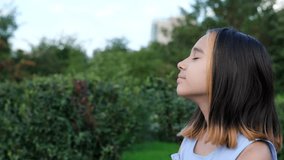 Portrait of a young beautiful preschool girl enjoying a warm summer day outdoors. Cute girl relaxing outdoors on the street, breathing fresh air. Profile of a child's face against the backdrop of a - Powered by Shutterstock - Get 15% off with code: PIKWIZARD15