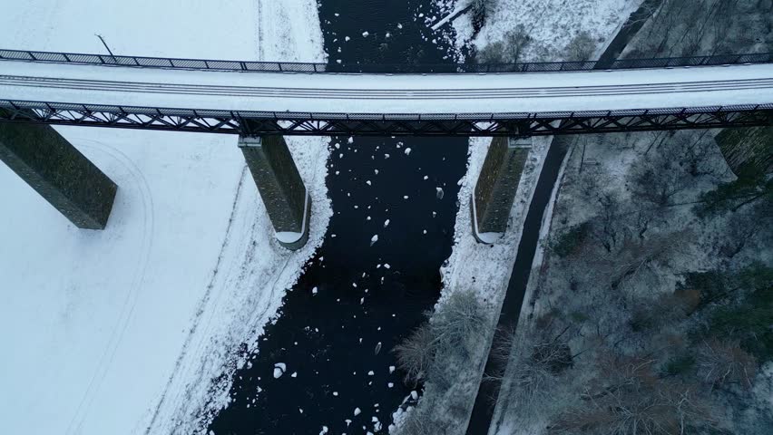 Looking directly down from Findhorn Viaduct icy river and snow covered landscape