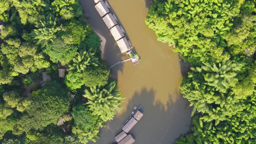 Top down aerial of River kwai floating hotels in brown river surrounded by jungle. Dolly forward, Kanchanaburi, Thailand. Royalty-Free Stock Footage #1109790945
