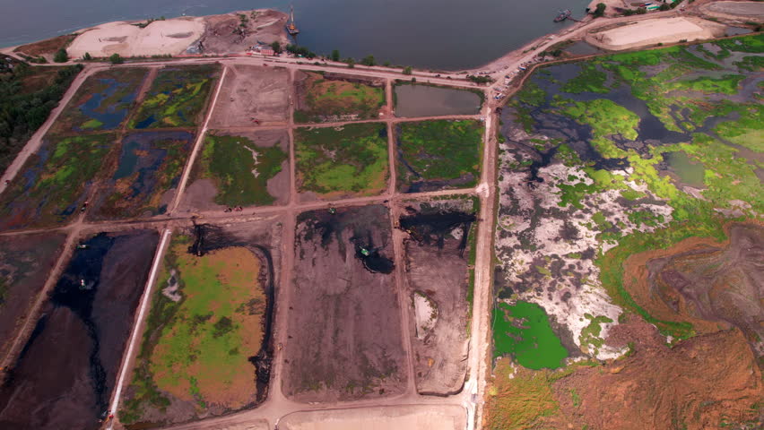 Silt fields with dirty water separated by ground mounds on riverbank aerial view. Swampy site for liquid evaporation and filtration