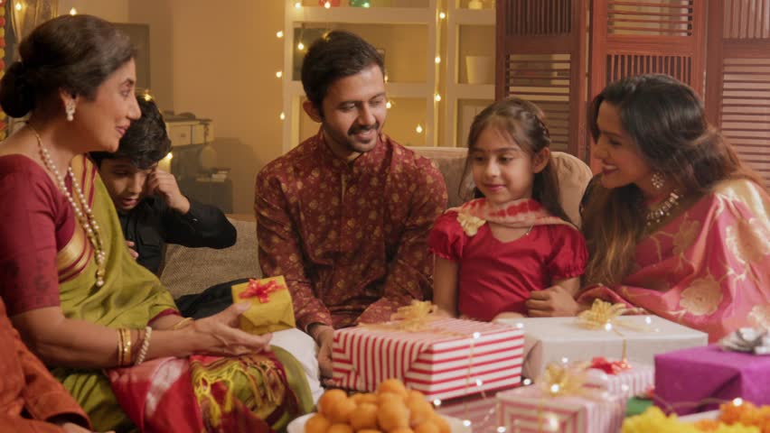 Cheerful Indian Elderly Parents Gift Presents to their young adult children during a family gathering on the auspicious occasion of Diwali festival in a decorated House. Bonding, relationship concept. Royalty-Free Stock Footage #1109794883